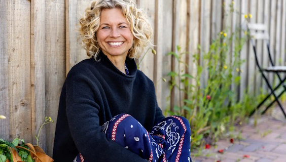 Portræt af smilende Betina Nygaard Bæk siddende ved plankeværk